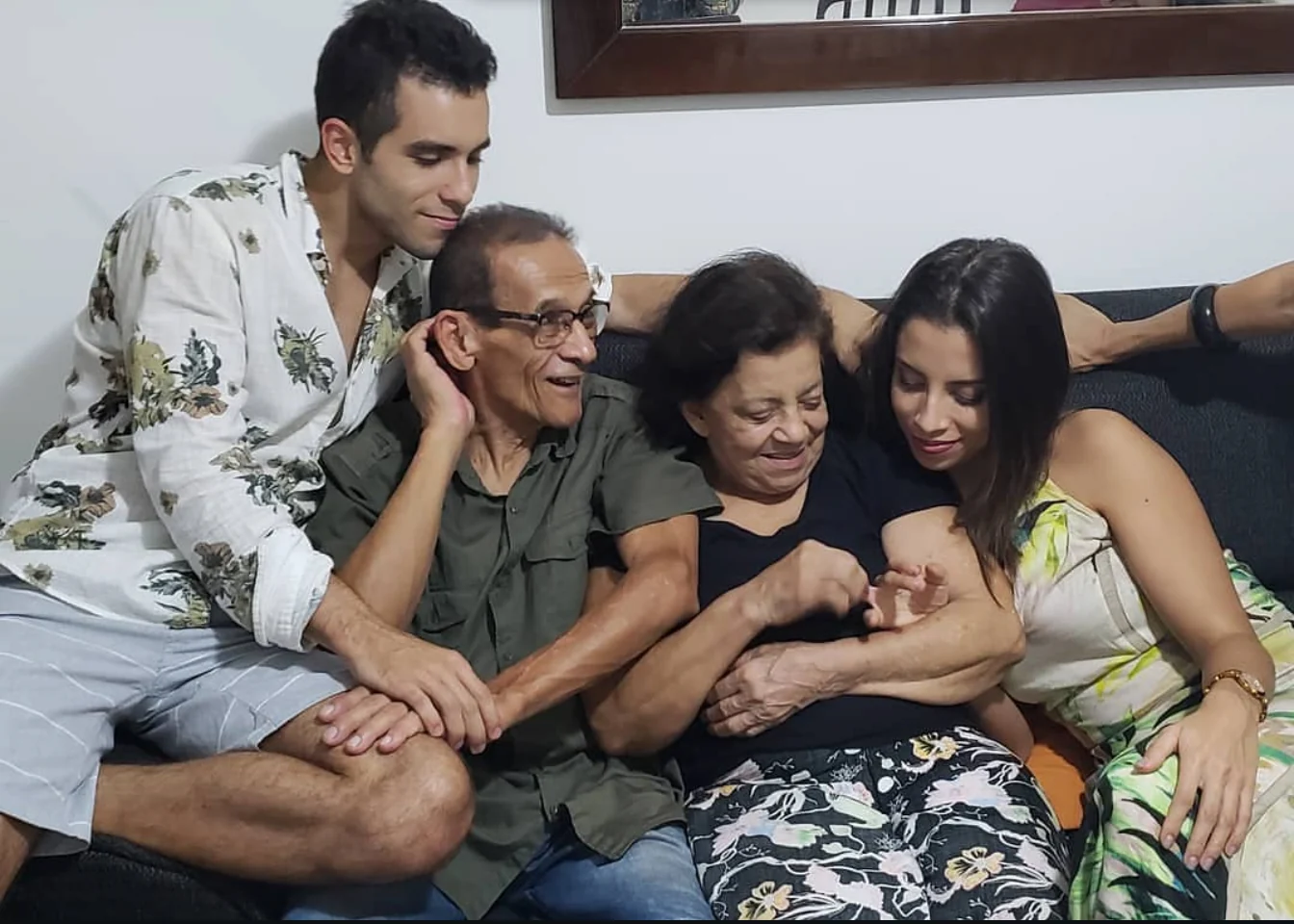 Raphael with his parents and family laughing together on a sofa