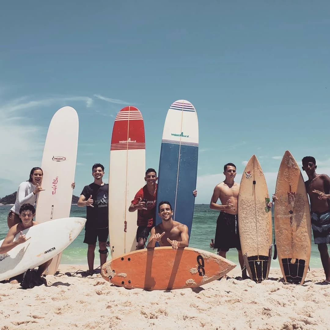 A group of surfers posing on the beach with their surfboards