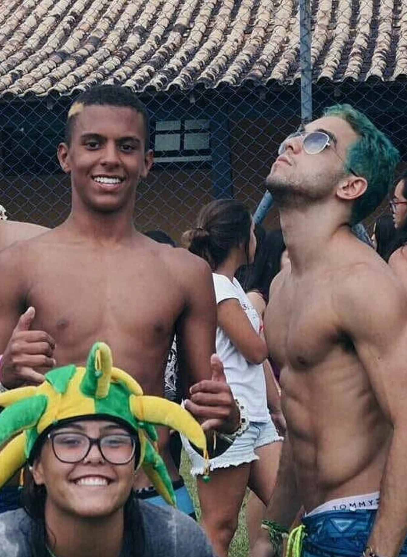 Raphael with teal hair, shirtless, smiling friends beside him