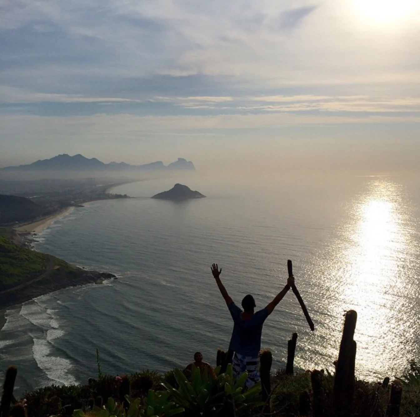 Silhouette with raised arms over the coastline at sunrise