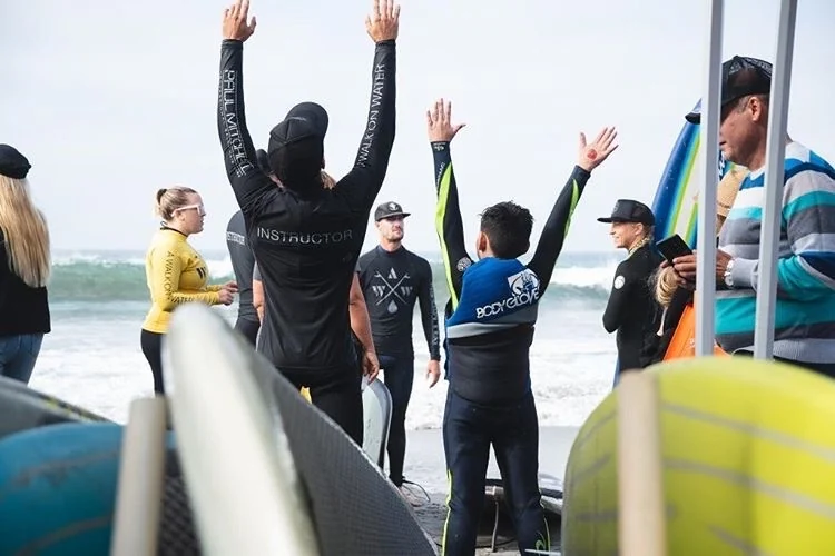A surf lesson group celebrating on the beach with surfboards