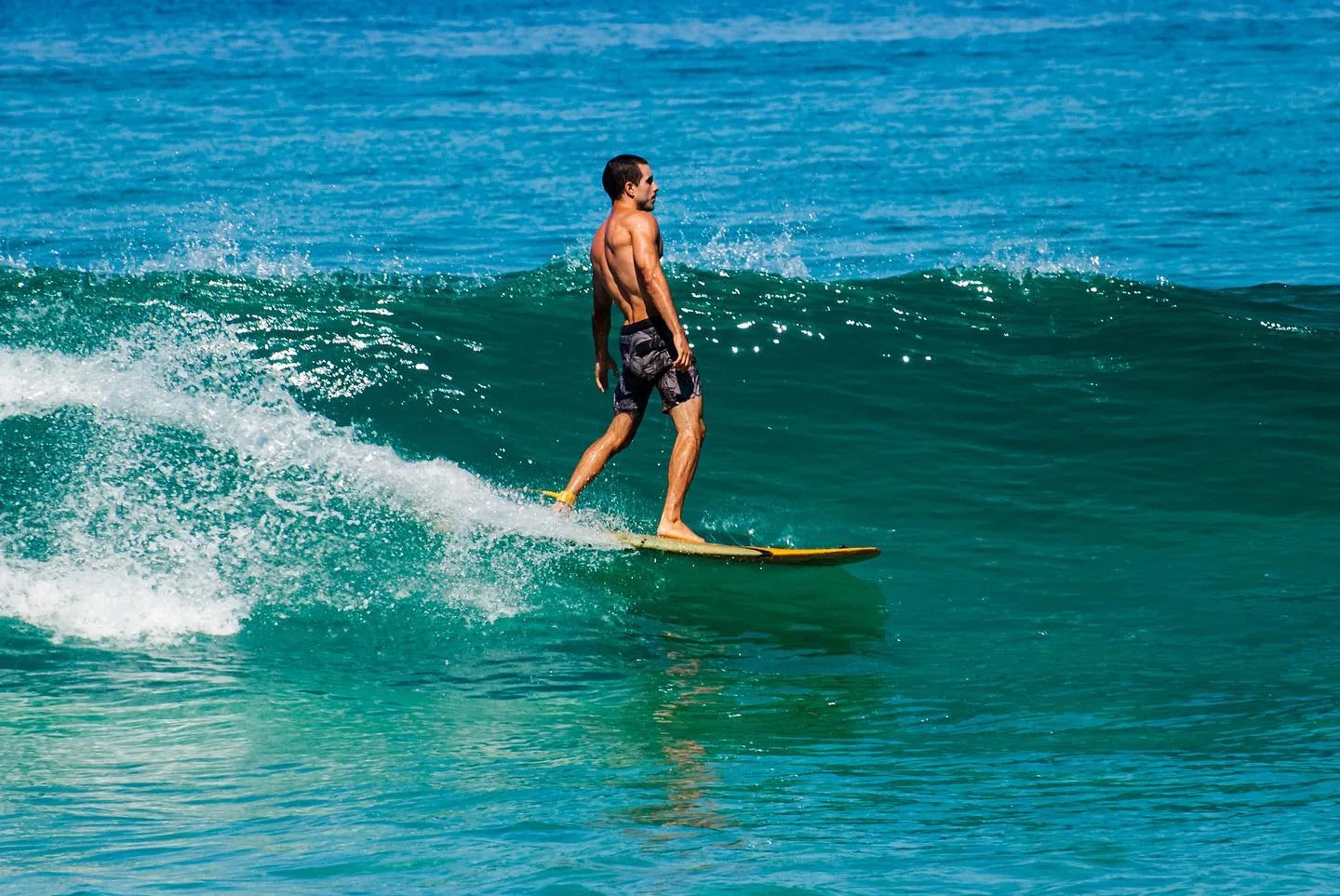 Raphael longboarding on a teal wave