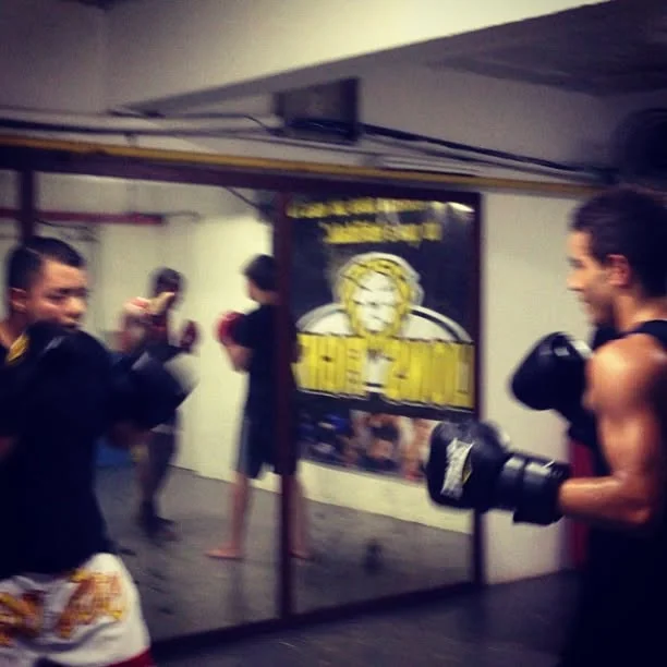 Raphael in boxing gloves sparring in front of a gym mirror